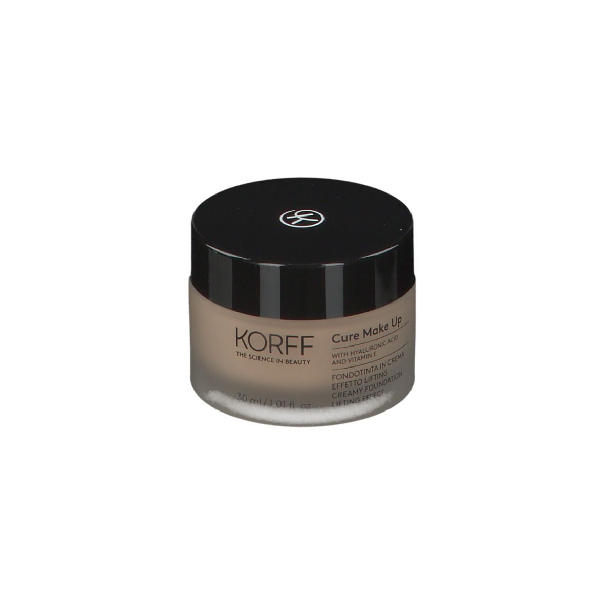 Crème beige dans un pot rond avec un couvercle noir. Un logo est sur le couvercle. KORFF Cure Make Up est écrit sur le pot.