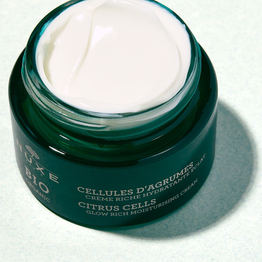 Geöffnete grüne Creme-Dose. Weiße Creme sichtbar. Aufschrift: NUXE BIO, CELLULES D'AGRUMES, CITRUS CELLS, GLOW RICH MOISTURISING CREAM.