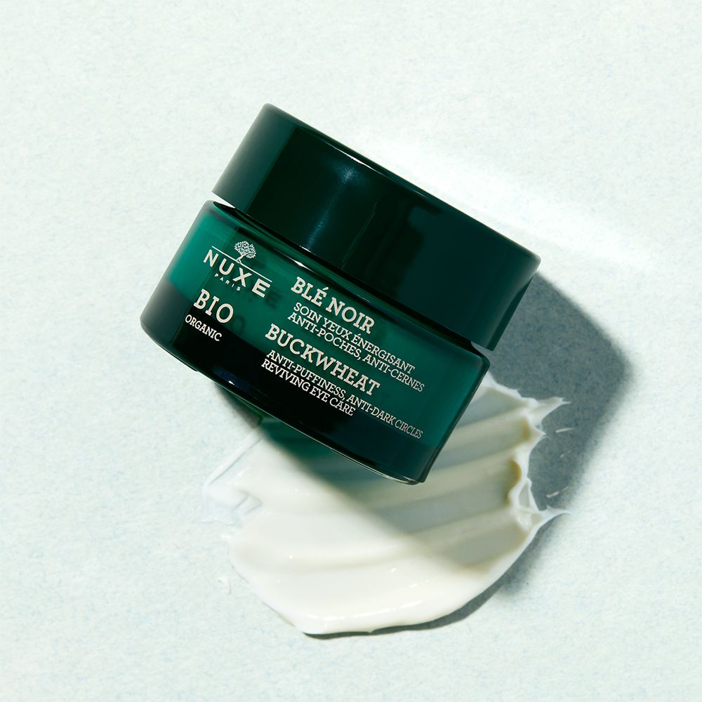 Dunkelgrünes Augenkonturpflege-Glas mit schwarzem Deckel und Creme-Klecks. Aufschrift: NUXE BIO, BUCKWHEAT, Anti-Puffiness, Anti-Dark Circles.