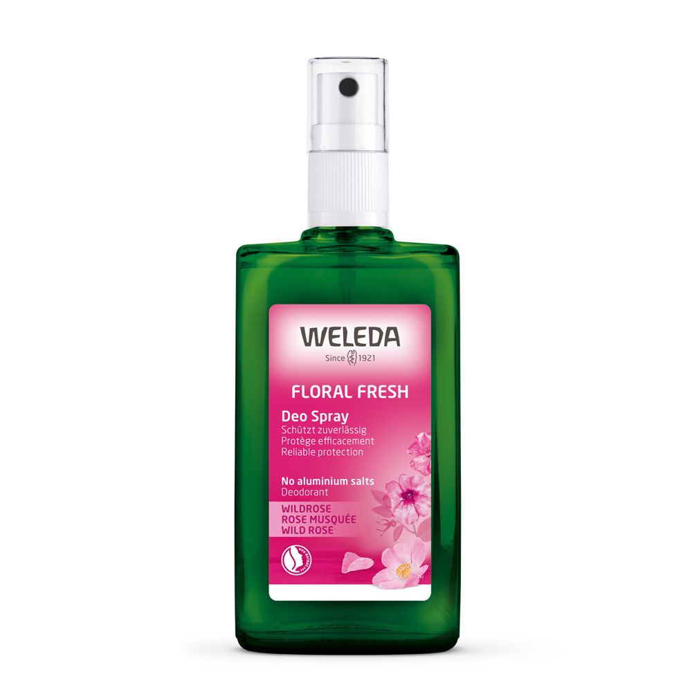 Flacon spray vert avec tête de pulvérisation blanche. Étiquette avec "WELEDA", "Floral Fresh" et informations. Fleurs roses.