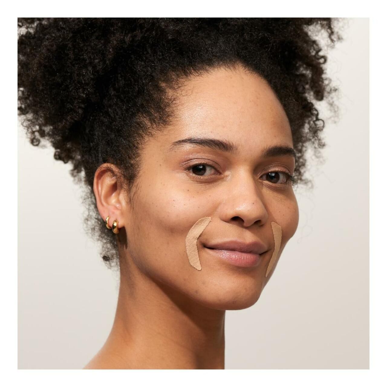 Frau mit zwei Mund-Patches auf der Wange. Hautfarbene Patches in Form eines gebogenen Streifens.