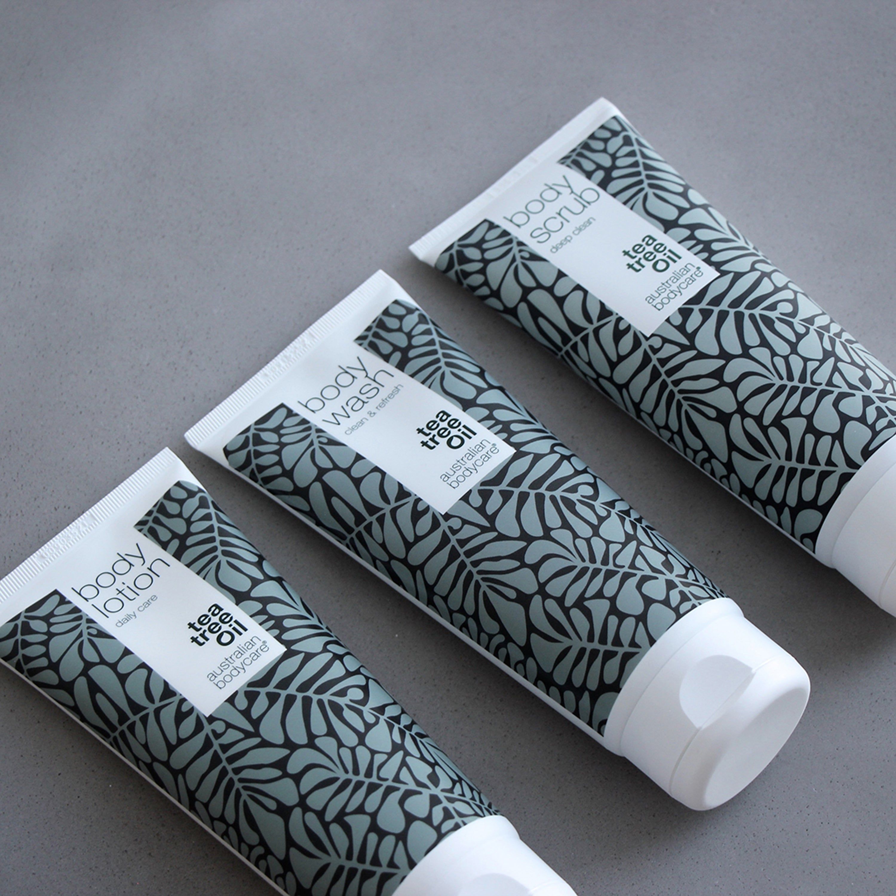 Trois tubes. Inscription : Body Lotion, Body Wash, Body Scrub, Tea Tree Oil, australian bodycare. Motif feuilles.