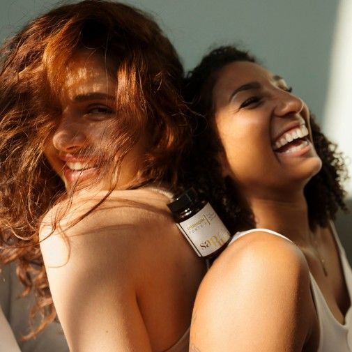 Deux femmes souriantes. L'une tient un flacon brun de capsules de spermidine. Inscription : Spermidine Forte +, 100% végétalien. Logo SAPURA.