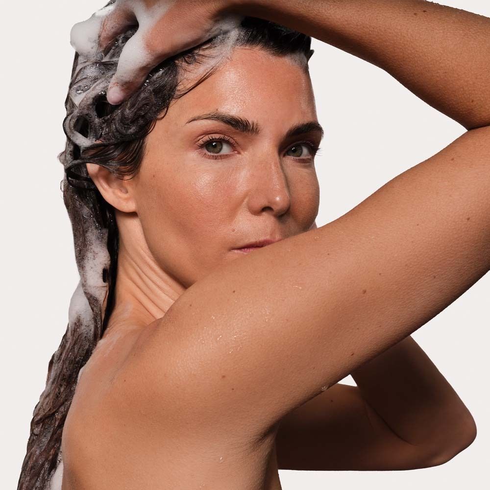 Une femme se lave les cheveux avec le shampooing ANNEMARIE BÖRLIND Hydro moussant.