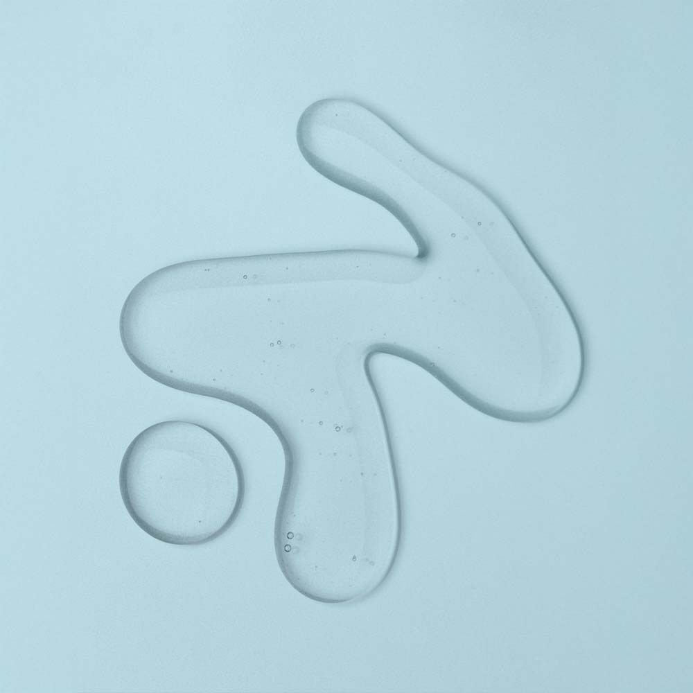 Goutte liquide transparente sur fond bleu clair.