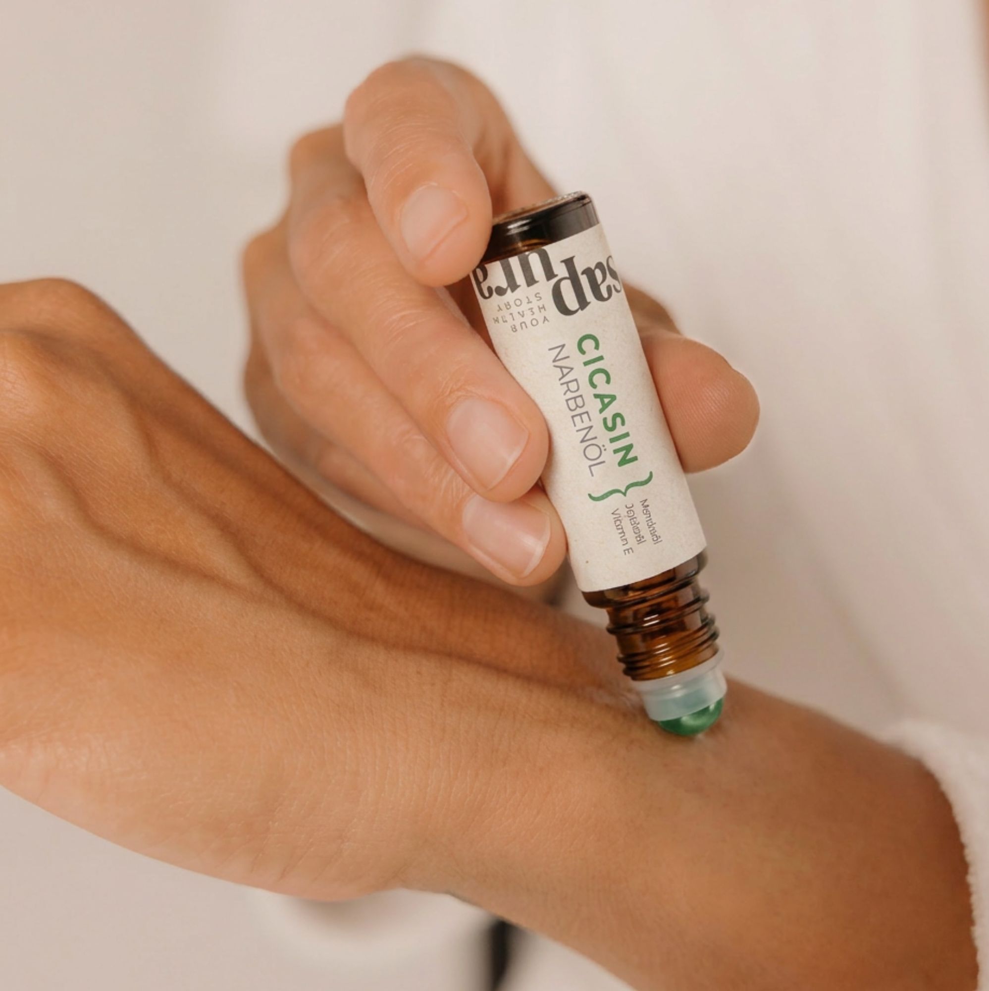 Une main applique de l'huile cicatricielle sur la peau du poignet avec un applicateur roll-on.