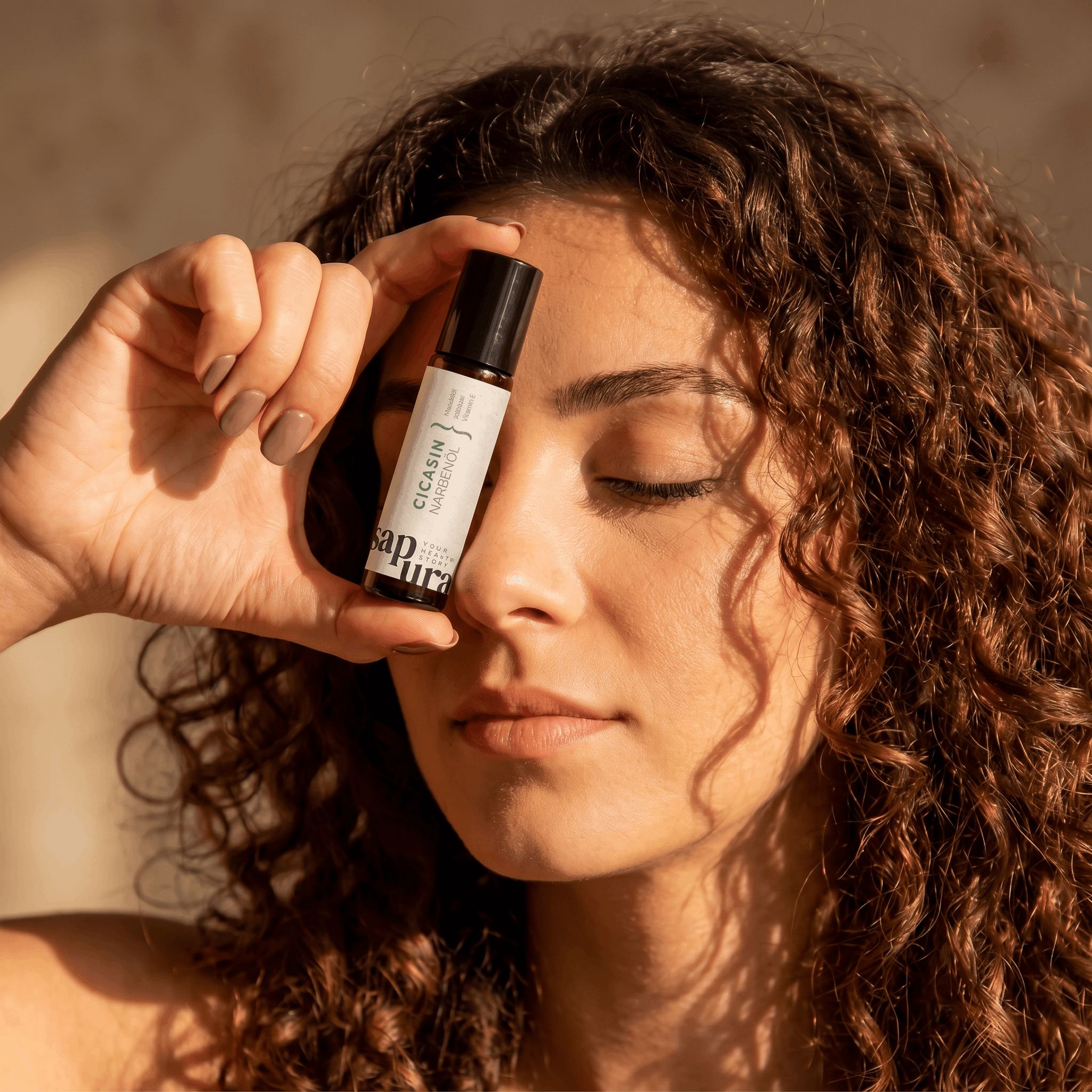 Une femme tient une petite bouteille d'huile cicatricielle devant son visage. L'étiquette est visible.