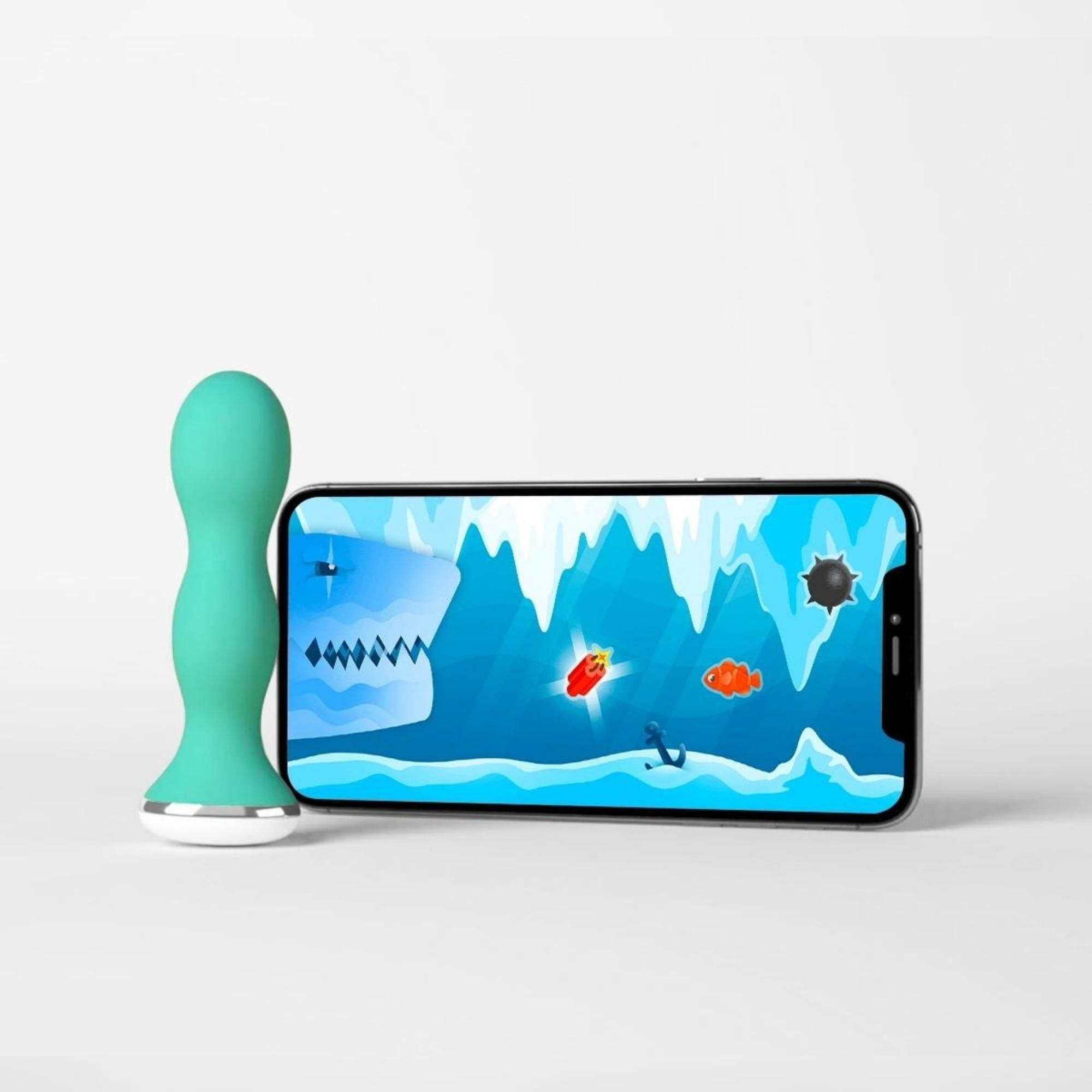 Türkisfarbenes Gerät mit weißer Basis neben einem Smartphone mit Spielbildschirm. Das Spiel zeigt eine Unterwasserszene.