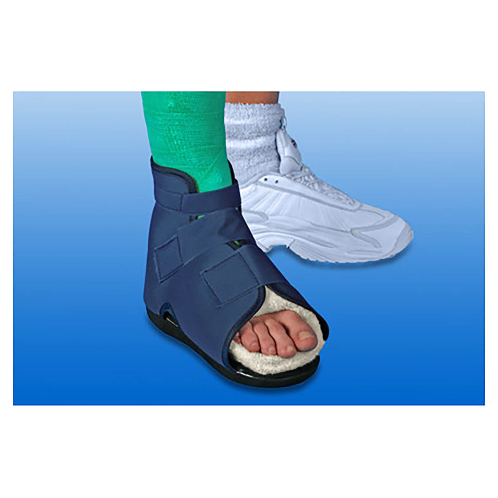 Blauer Gehschuh mit Klettverschlüssen und weichem Innenfutter. Fuß in grünem Verband. Im Hintergrund ein weißer Sportschuh.