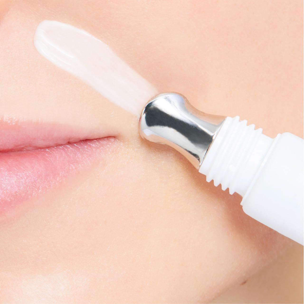Gros plan du visage. Applicateur Cellfiller-XT sur les lèvres. Crème appliquée. Fond blanc.