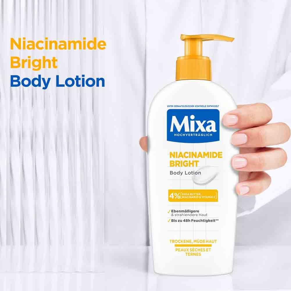 Person hält eine Flasche Mixa Niacinamide Bright Body Lotion. Gelber Pumpkopf, weiße Flasche.
