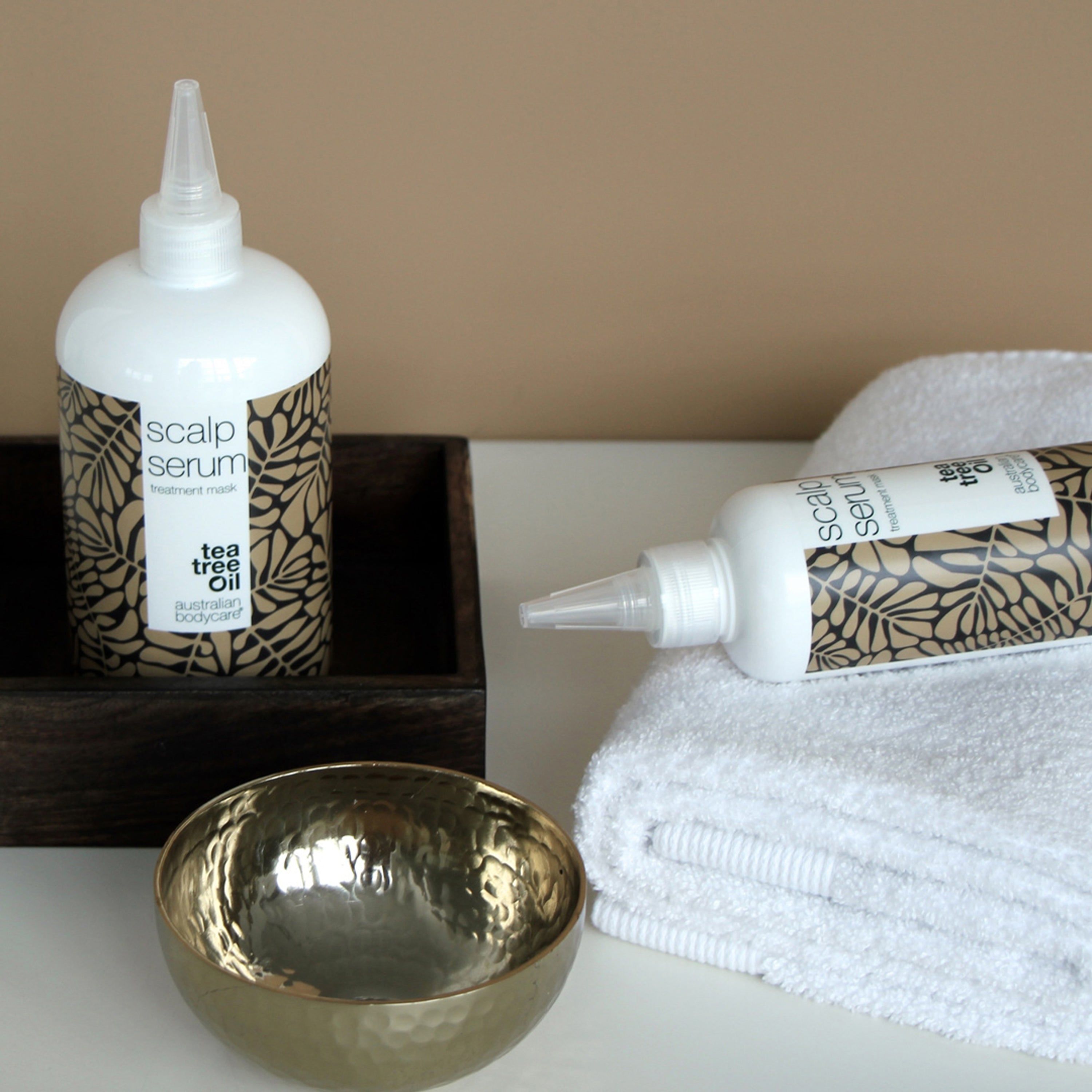 Flacon de sérum et bol. Inscription : Scalp Serum, tea tree oil, australian bodycare. Serviette et bol.