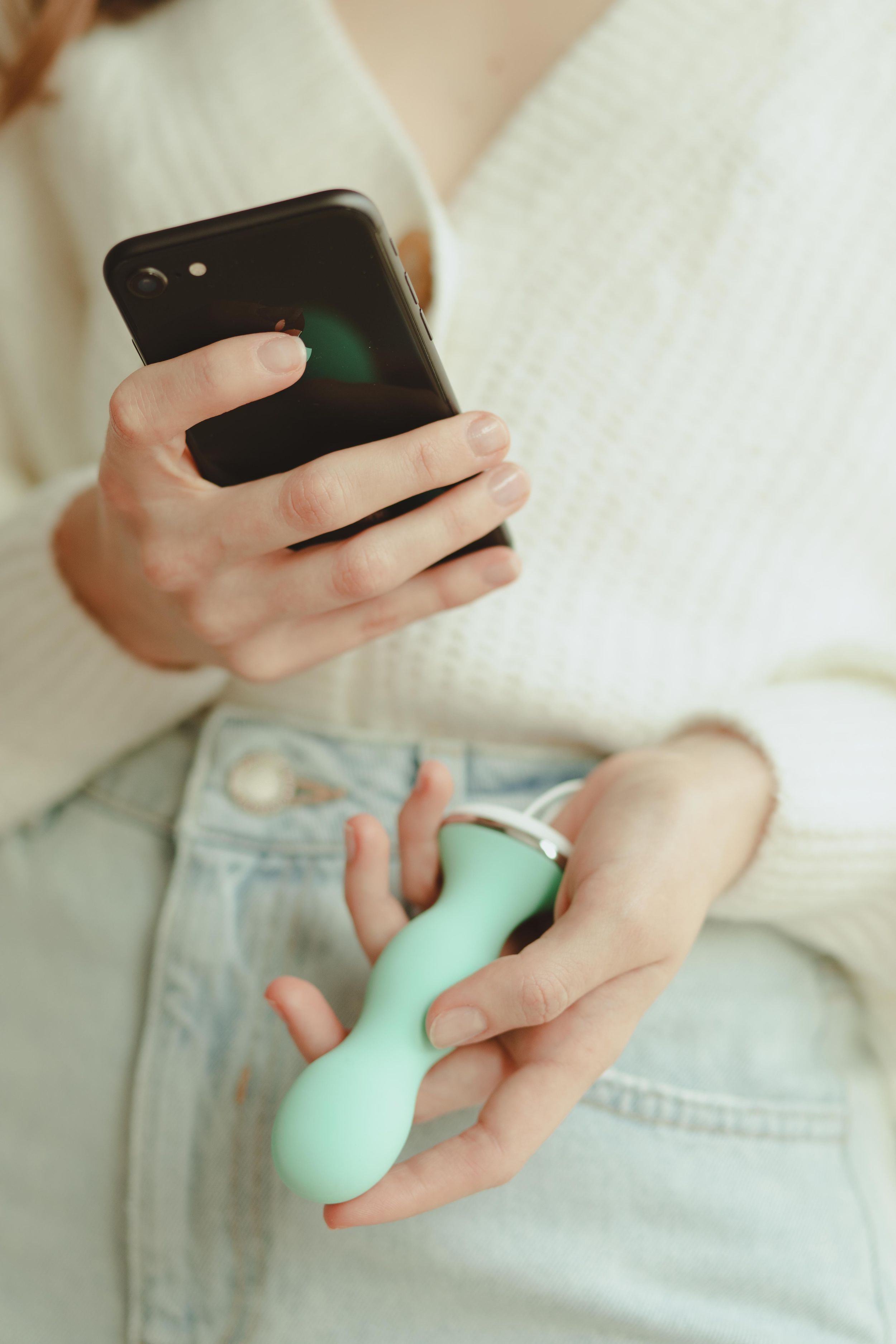 Person hält ein türkisfarbenes Gerät und ein Smartphone. Das Gerät hat eine weiße Basis.