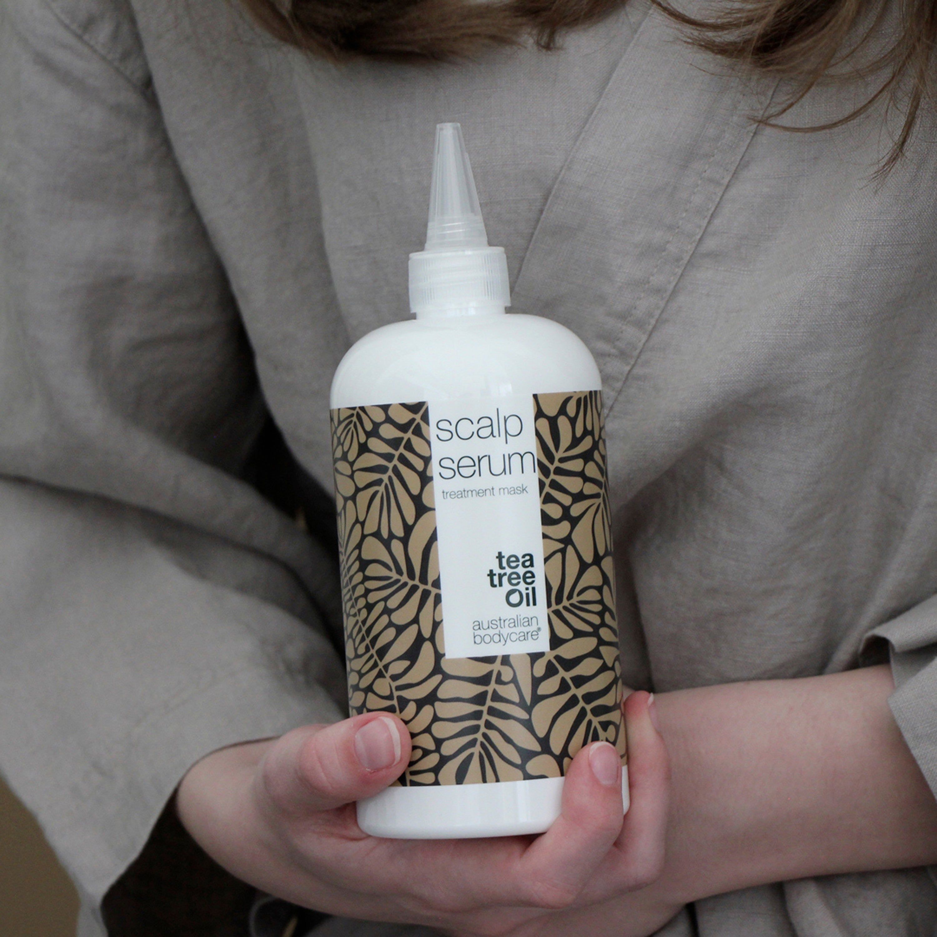 Personne tenant un flacon de sérum. Inscription : Scalp Serum, intensive scalp treatment, tea tree oil, australian bodycare.