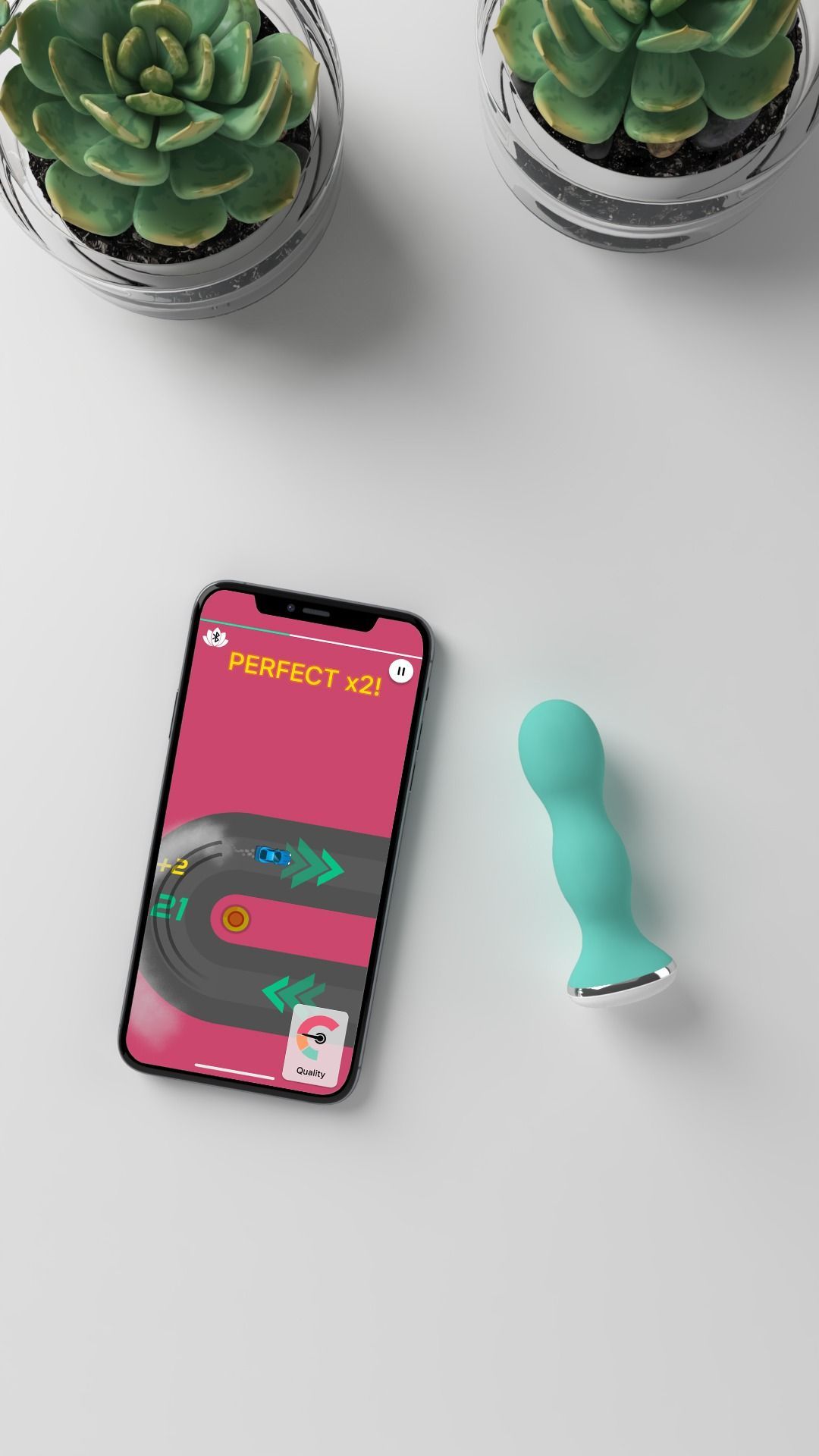 Türkisfarbenes Gerät neben einem Smartphone mit Spielbildschirm. Das Spiel zeigt eine Rennstrecke.