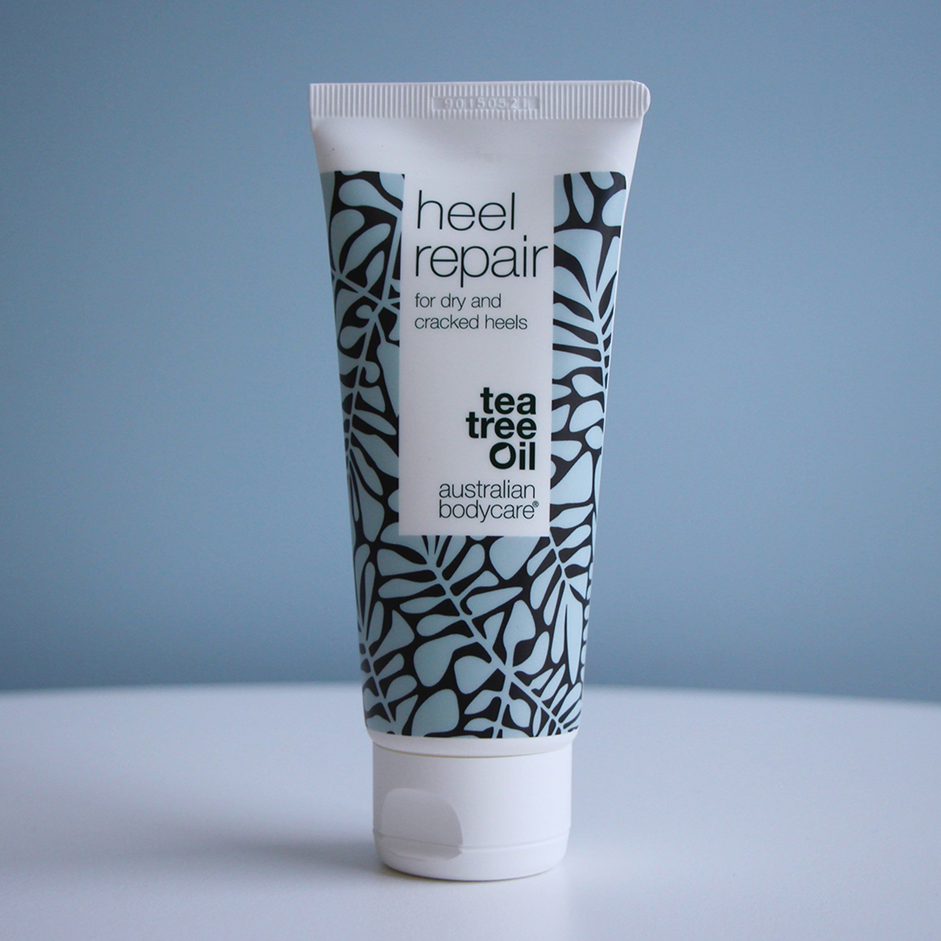 Tube de crème pour talons. Blanc, floral, texte: Heel Repair, pour talons secs et crevassés. Marque: Australian Bodycare. Fond bleu.