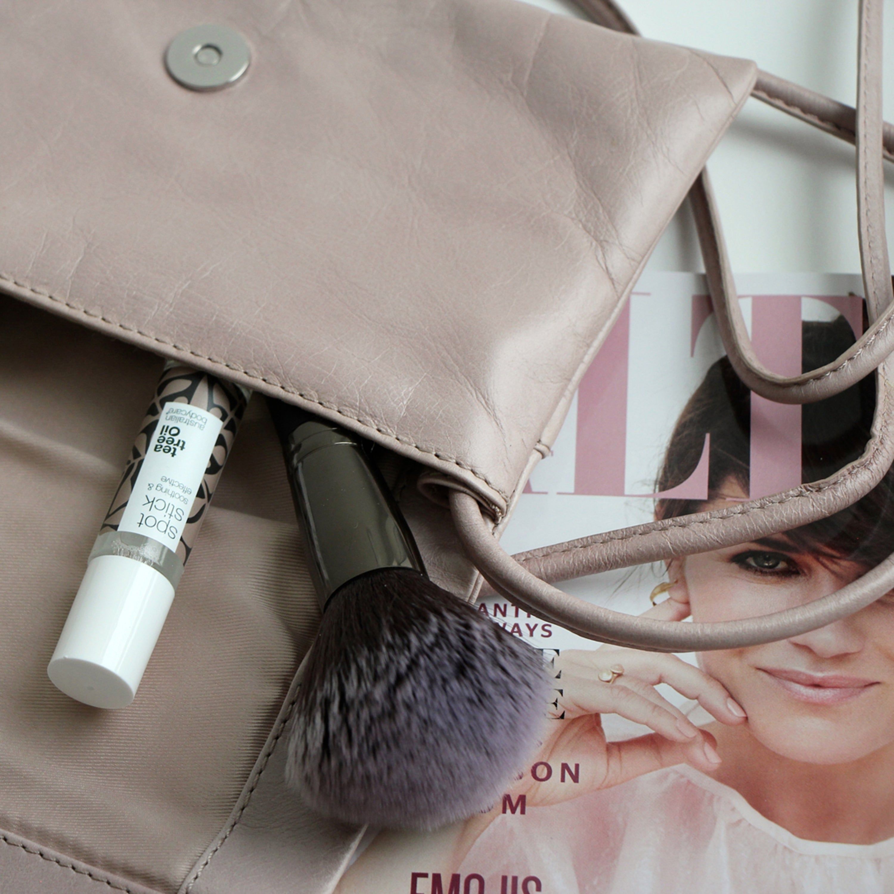 Roll-on et pinceau de maquillage dans un sac à main. Inscription : Spot Stick, Australian Bodycare.