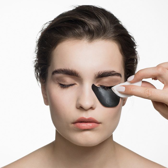 Visage d'une femme aux yeux fermés. Une main tient un coton sur une paupière.