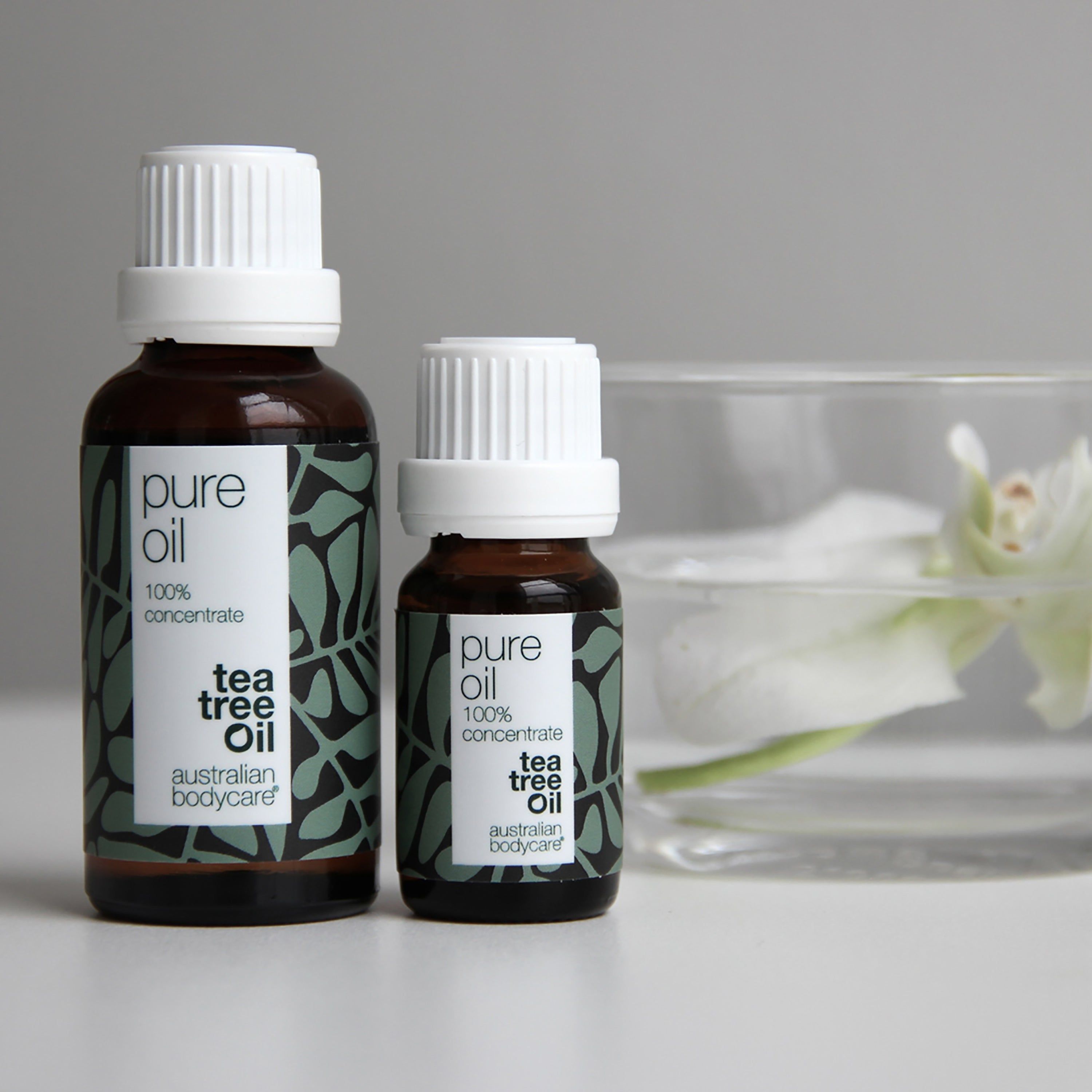 Deux flacons en verre brun avec bouchons blancs. Étiquette avec texte : Pure Oil, 100% concentrate, Tea Tree Oil, Australian Bodycare.