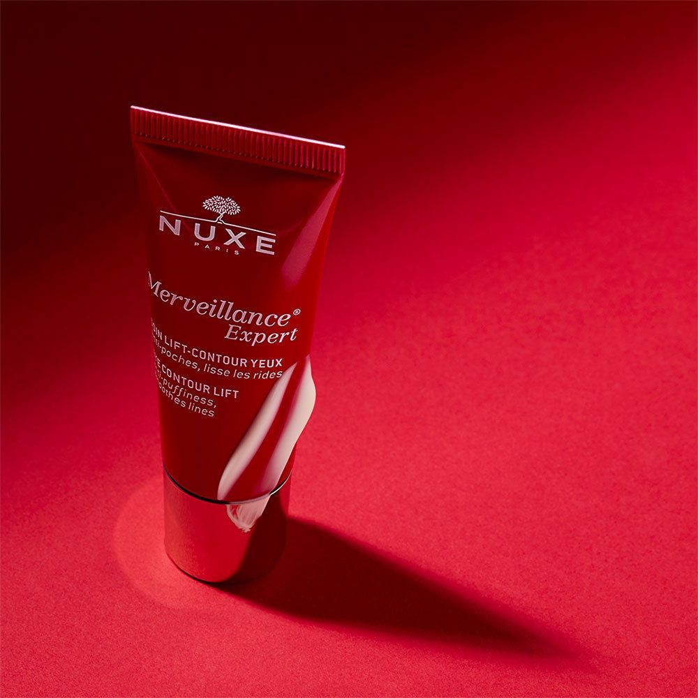 Tube rouge sur fond rouge. Inscription: NUXE, Merveillance Expert. Crème blanche sortant du tube.