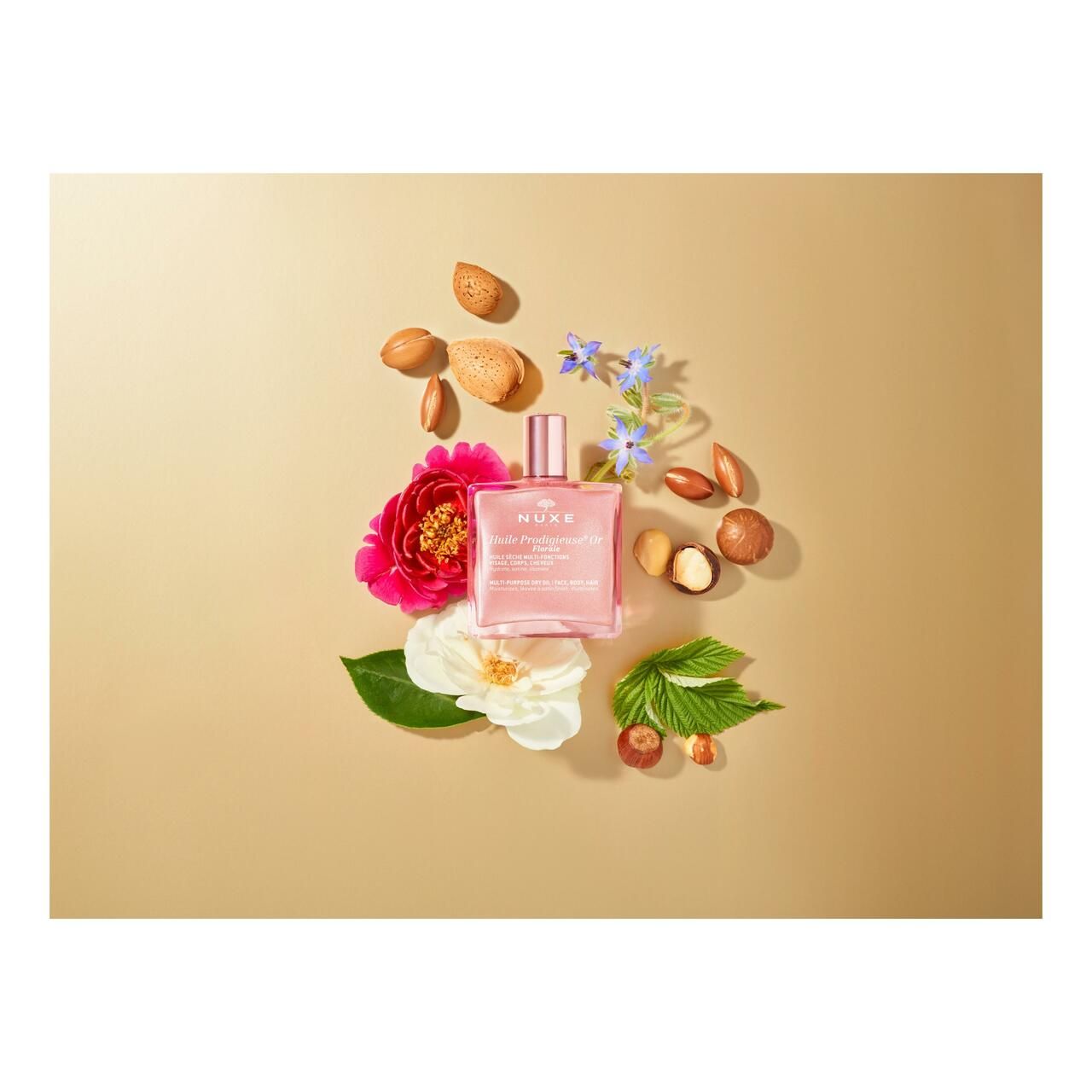 Nuxe Huile Prodigieuse® Or Florale. Rosa Flasche mit goldfarbenem Verschluss. Produkt auf beigem Hintergrund.