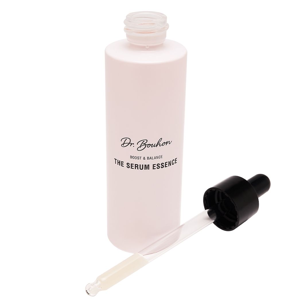 Leere, rosa Flasche mit schwarzem Deckel und Pipette daneben. Aufschrift: Dr. Bouhon, THE SERUM ESSENCE.