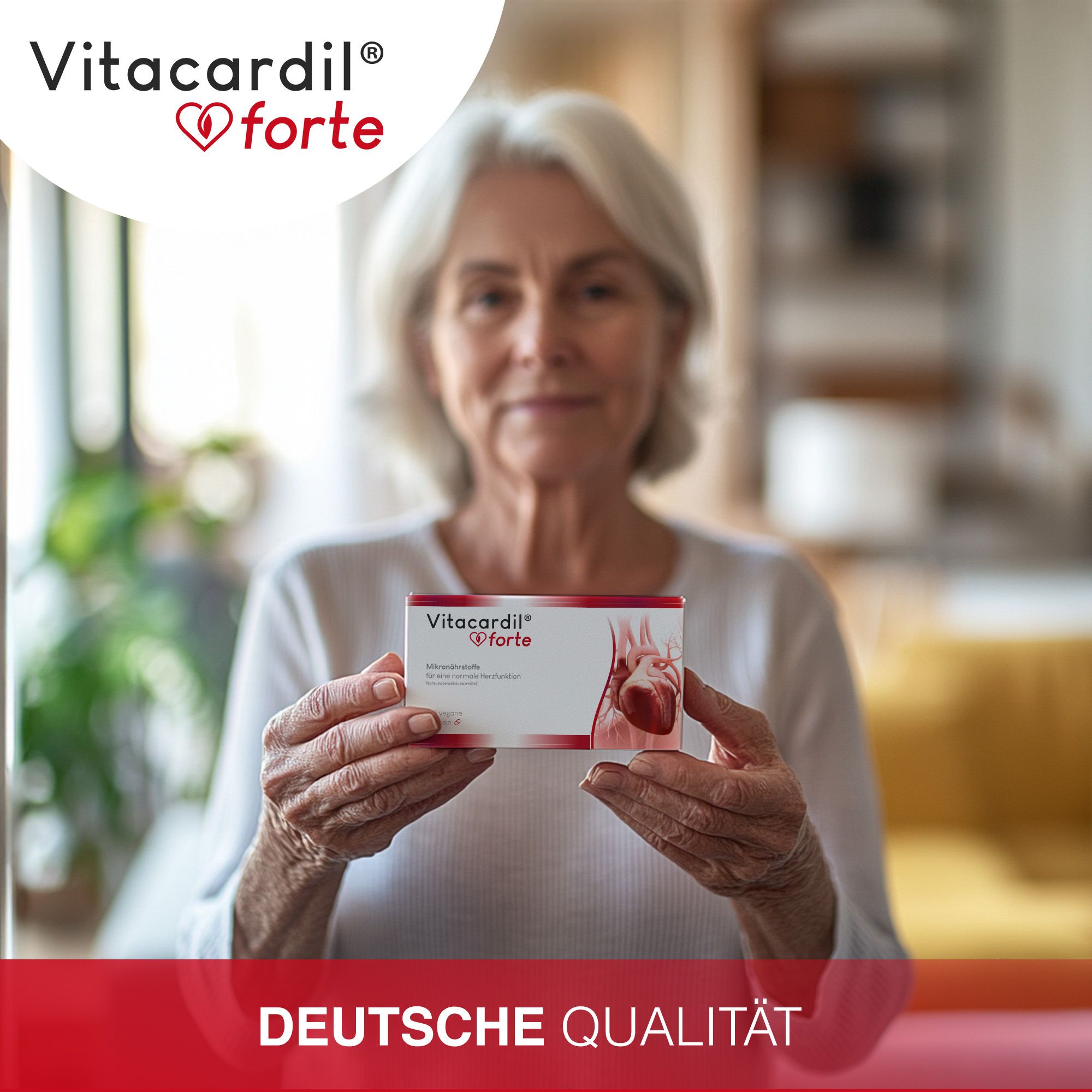 Une femme âgée tient une boîte de Vitacardil® forte. Un cœur est représenté sur l'emballage. Le texte "Deutsche Qualität" est visible.