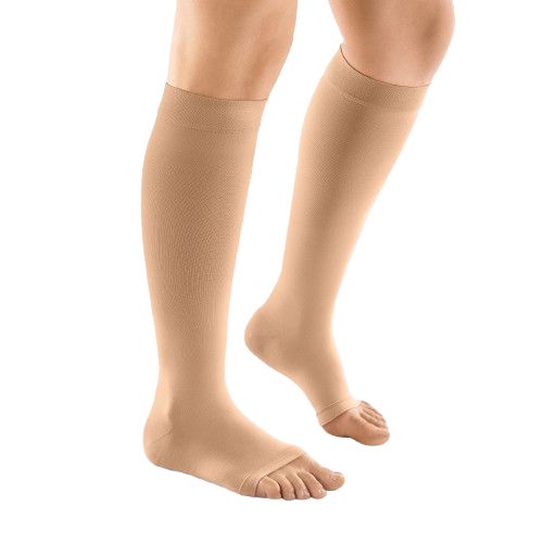 Bas de compression beiges à bout ouvert. Vue latérale des jambes d'une personne portant les bas.